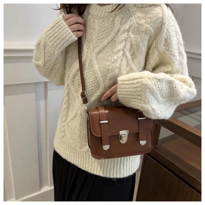 Piccola borsa a tracolla vintage marrone in similpelle con fibbia argento su un maglione