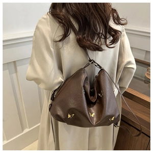 Close-up of brown leather bag featuring golden metal butterfly details and soft texture