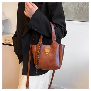 Close-up of brown vintage tote bag featuring a textured finish and braided tassel detail
