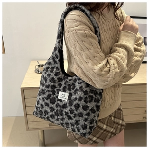 Detail shot of leopard print plush shoulder bag featuring a white woven brand label