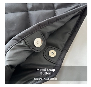 Close-up of metallic magnetic closure and diamond quilted texture on black tote bag