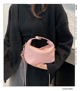 Detail of pink crossbody bag with pebbled leather texture and gold twist-lock closure