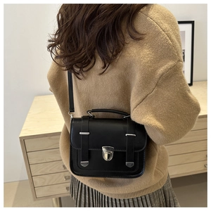 Model wearing black matte leather crossbody bag with silver buckle and adjustable strap