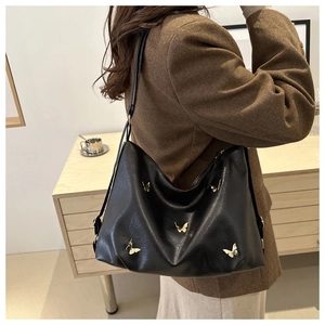 Dettaglio borsa tote in ecopelle nera con farfalle dorate e tracolla lunga stile casual chic