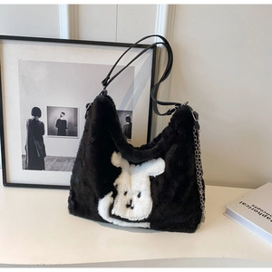Detail of a plush black faux fur tote bag with white rabbit pattern and metal chain strap