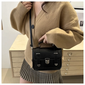 Detail view of black vintage square bag with silver metal buckle and top handle