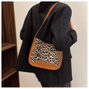 Gros plan du sac léopard avec bandoulière en cuir marron porté avec un blazer gris