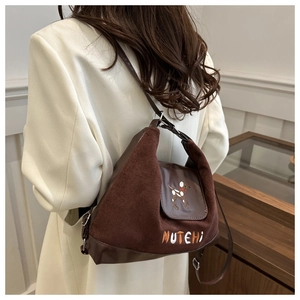 Detailed view of suede and leather backpack with brown dog embroidery and MUTEHI text
