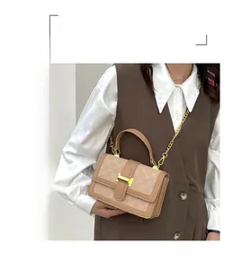 Detail of beige checkered embossed handbag with gold buckle and chain strap on model