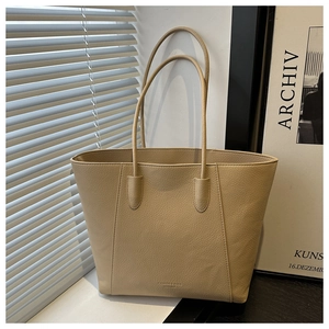 Detail of beige tote bag with pebbled texture and thin straps in natural light