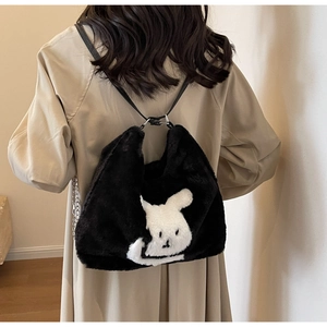 Detail of plush shoulder bag with white rabbit pattern and slim black strap on model