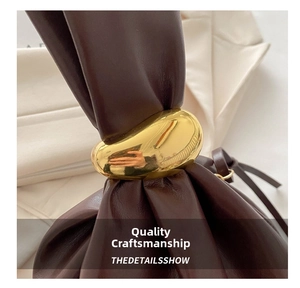 Detail of dark coffee leather bucket bag with a large smooth oval golden metal buckle