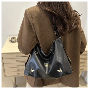Detail of black hobo bag with pleated leather texture and gold butterfly ornaments