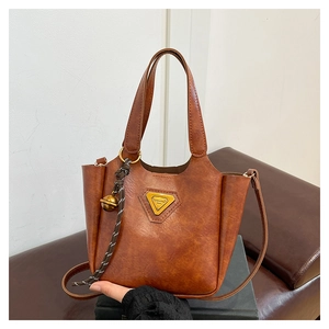 Detailed close-up of brown PU leather bag with vintage texture and golden triangle badge