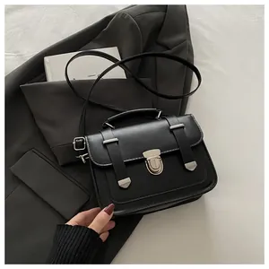 Detail of black matte leather crossbody bag with buckle straps and metal clasp