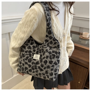 Close-up of grey leopard faux fur shoulder bag with branded label and plush texture