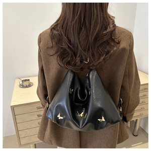 Dettaglio borsa in ecopelle nera con fibbia a farfalla dorata e design a pieghe morbide
