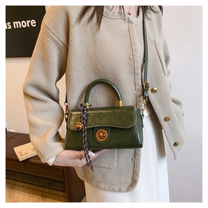 Elegante borsa a mano in pelle verde scuro abbinata a un outfit beige moderno