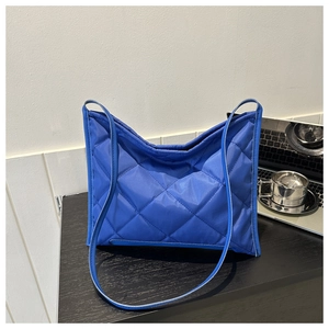 Detailed view of royal blue quilted tote bag with diamond stitching on wooden desk