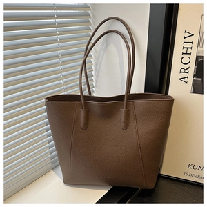 Detail of dark brown lychee textured leather tote with minimalist straps and fine stitching