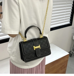 Detail of black checkered crossbody bag with gold H-buckle and elegant chain strap