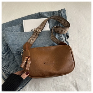 Detail of vintage brown bag with wide woven strap and decorative fashion logo