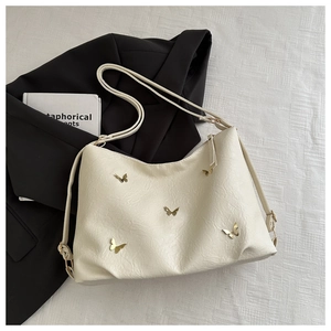 Macro detail of creamy white PU leather tote bag with 3D golden butterfly ornaments