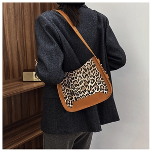 Close-up of leopard print hobo bag with brown leather trim worn by a model in a retro setting