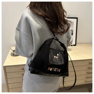 Detail of black canvas tote bag with embroidered puppy and MUTEHI text worn by a model