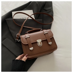 Detailed view of brown vintage square bag with silver metal buckle on grey suit fabric