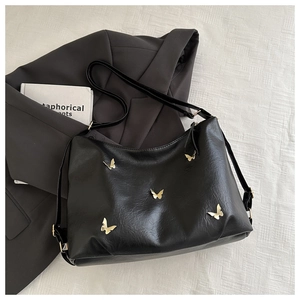 Detail of black faux leather tote with golden butterfly charms and adjustable strap