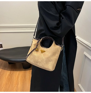 Detail of khaki bucket bag showing brown leather handles and golden triangle hardware