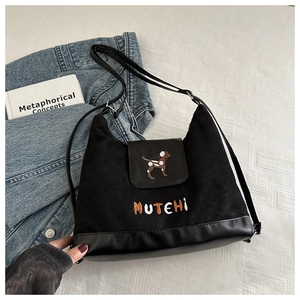Detail of black suede backpack featuring dog embroidery and MUTEHI text on texture cloth