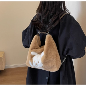 Detail of camel plush tote bag with white rabbit motif and metal chain strap accent