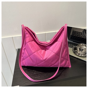 Detail of fuchsia quilted nylon tote bag with rhombus patterns on a desk