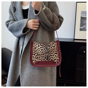 Close-up of leopard print tote bag with burgundy faux leather trim and shoulder strap