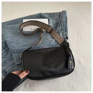 Detail of black faux leather bag with vintage texture and bohemian wide strap