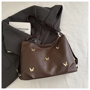 Detail of brown lychee leather shoulder bag with decorative gold butterfly hardware