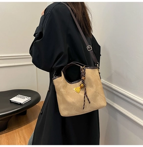 Detail of khaki bucket bag with braided knot handle and metal triangle logo accent