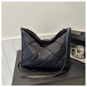 Detail of black quilted oxford tote bag with diamond pattern on a desk with laptop