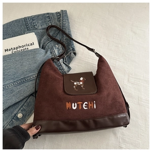 Detail of vintage brown suede tote featuring cartoon dog embroidery and reinforced base