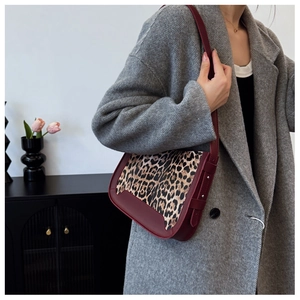 Close-up of wine red leather and leopard print tote bag worn with a grey wool coat