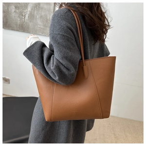 Close-up of brown litchi leather tote bag with fine stitching and golden embossing
