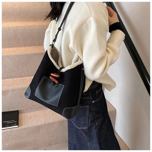 Detail of plush tote bag with wooden horn buckles and a leather patch pocket shown in use
