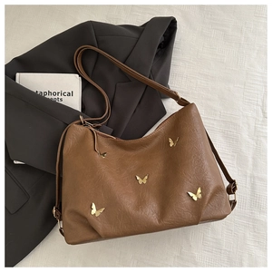 Detail of five golden butterfly hardware accents on a vintage brown PU leather bag