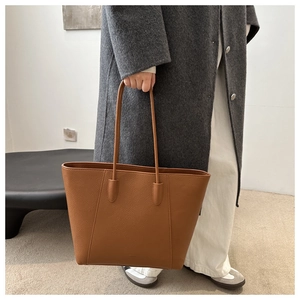 Detailed view of brown lychee texture leather tote bag worn with grey wool coat