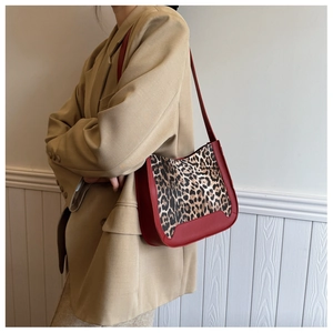 Detail of red and leopard print suede bucket bag worn with a khaki blazer