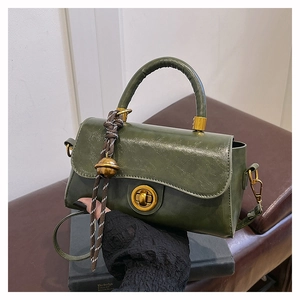 Dettaglio borsa vintage in pelle verde con chiusura in metallo e ciondolo a fune