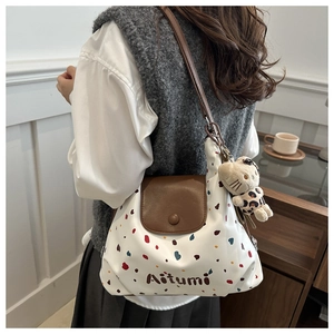 Dettaglio della borsa tote a pois con tracolla in pelle marrone indossata da modella
