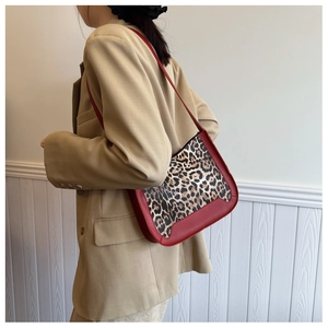 Détail du sac à bandoulière bordeaux avec motif léopard porté sur un blazer kaki